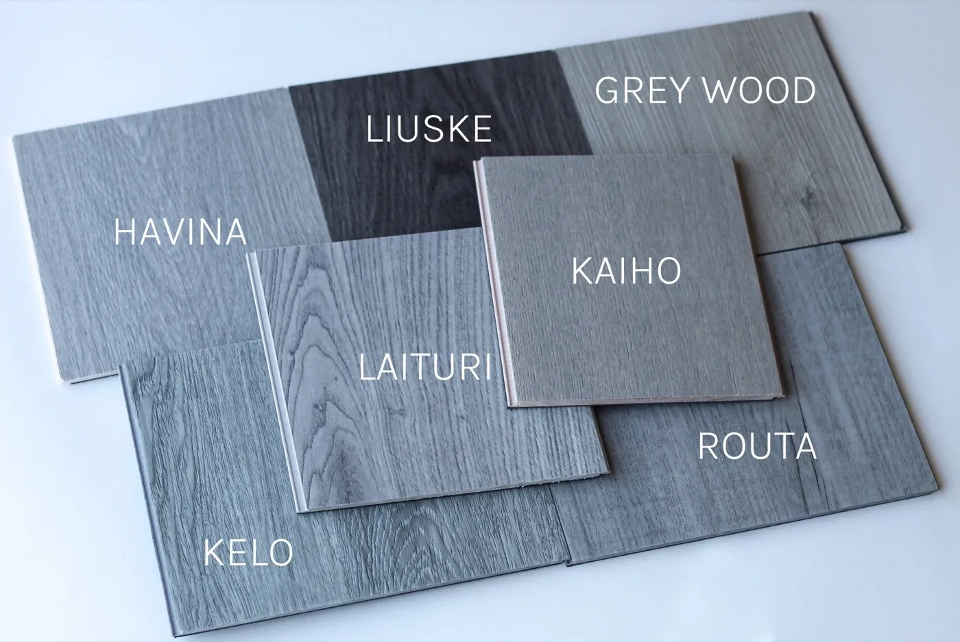 Harmaat lattiamallit vierekkäin: Kelo, Havina, Laituri, Liuske, Routa, Grey Wood ja kovapuulattia Kaiho